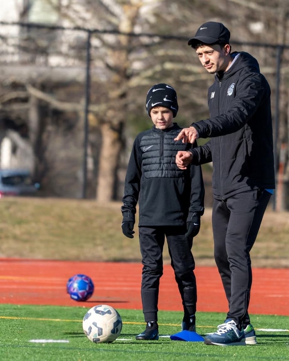 Coach Gabriel Padilla coaching a young soccer player.